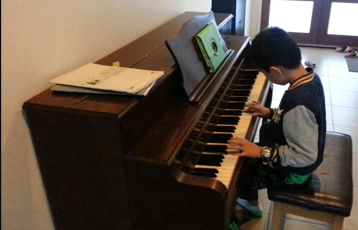 Isaac playing the family's first second-hand upright piano