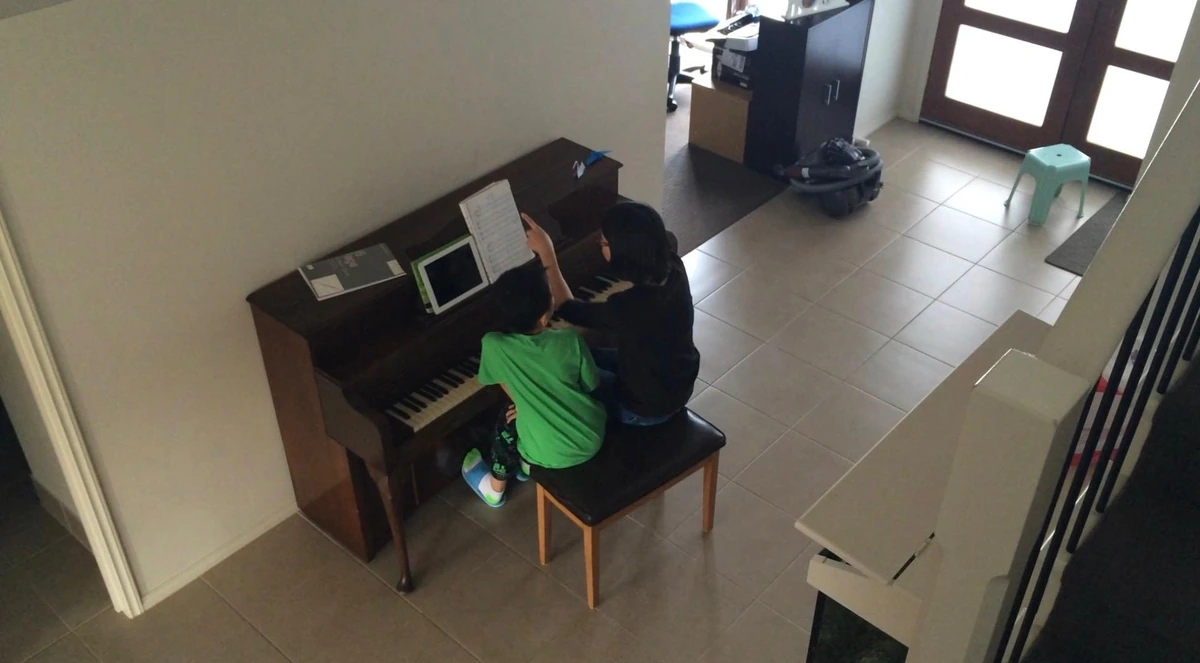 Isaac and his mum learning together at the upright piano