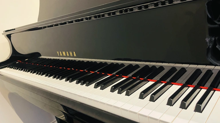 A diagonal view of the Yamaha grand piano keyboard, with gold lettering and red felt